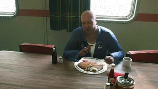 An angry bald man eating a delicious looking fry up on a oil rig